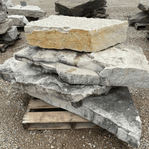 Stack of large natural stone slabs on a wooden pallet at Whispering Hills Nursery.