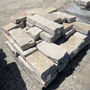 Stacked beige and gray stone pavers on a pallet at Whispering Hills Nursery.