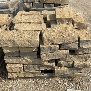 Stack of rough-cut natural stone pavers for landscaping or construction.